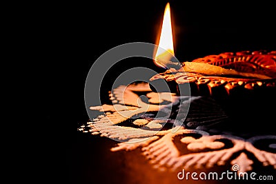 Beautiful glowing terracotta lamp and white rangoli design on black background with copy space in the left. diwali concept Stock Photo