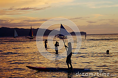 Beautiful golden sunset over fishing boats and people in water Editorial Stock Photo