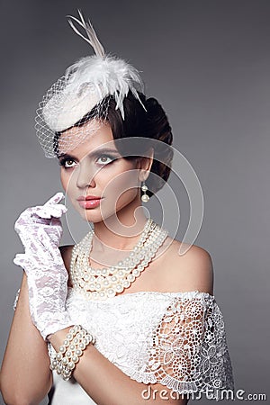 Beautiful gorgeous woman with elegant wavy hairstyle, bright make up. Fashion brunette wearing pearls jewelry, retro hat and lace Stock Photo