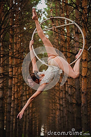 Beautiful and graceful aerial gymnast does exercises on the ring Stock Photo