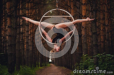 Beautiful and graceful aerial gymnast performs exercises on the air ring Stock Photo