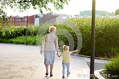 Beautiful granny and her little grandchild walking together in park Stock Photo