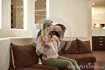 Beautiful granny is smiling while granddaughter is telling her something Stock Photo