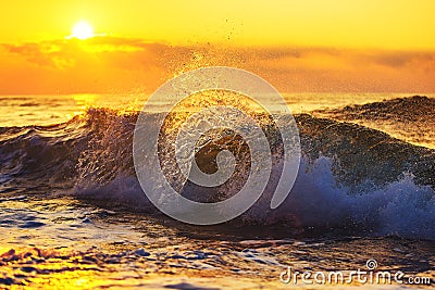 Golden sunrise and splashing blue sea waves near the beach Stock Photo