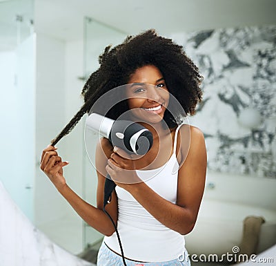 Beautiful hair requires proper care. Portrait of an attractive young woman blowdrying her hair at home. Stock Photo