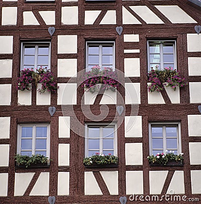 Beautiful half-timbered white house with red geraniums on the windowsill Stock Photo