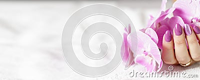 Beautiful hands with fresh pink lilac manicure with orchid flower Stock Photo