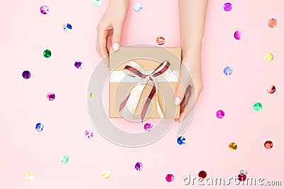 Beautiful hands girl hold gift box present craft paper on pink background, top view. Concept Christmas, New Year Stock Photo