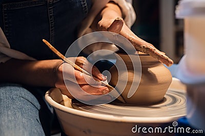 Beautiful hands of a young girl potter in the process of sculpting a vase with clay and tools. Stock Photo