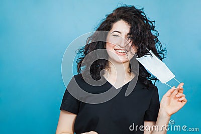 Beautiful happy black haired woman taking off medical antiviral mask. Stock Photo