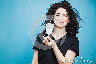 Beautiful happy black haired woman taking off medical antiviral mask. Stock Photo