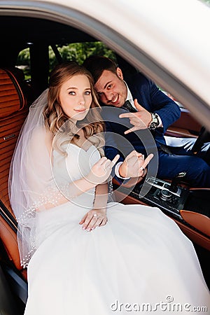 A beautiful and happy bride and the groom sit in cars. Rent transport Stock Photo
