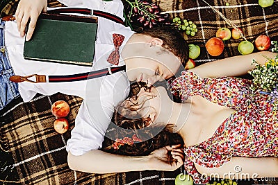 beautiful happy bride and stylish retro groom lying on tweed blanket, cuddling and relaxing, picnic in sunny meadow Stock Photo