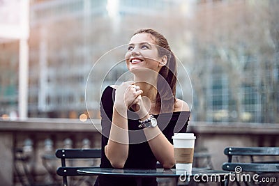 Beautiful happy businesswoman sitting in city park during lunch time or coffee break with paper coffee cup. Stock Photo