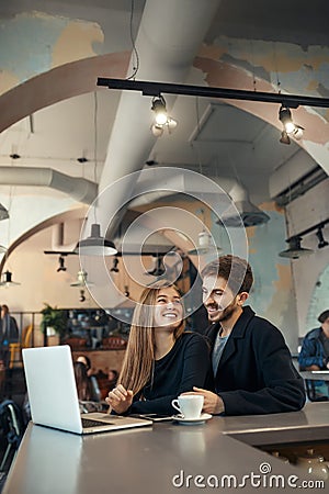 Beautiful happy couple working on laptop computer during coffee break in cafe bar Stock Photo