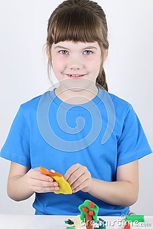 Beautiful happy girl molds toys from plasticine Stock Photo