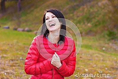 Beautiful, happy girl with perky smile in red jacket is in the forest Stock Photo