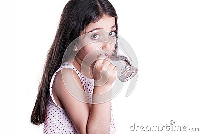 Beautiful happy little girl with long dark hair and dress holding glass of water. Stock Photo
