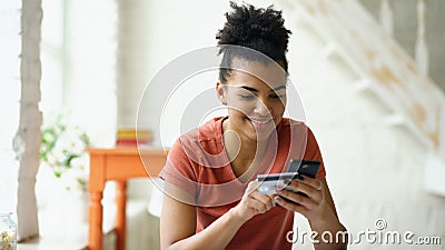 Beautiful happy mixed race woman online banking using smartphone shopping online with credit card at home lifestyle Stock Photo