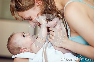 Beautiful happy mother playing with newborn baby Stock Photo