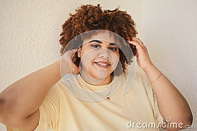 Beautiful happy smiling curvy plus size African black woman afro hair with make up posing in beige t-shirt on white Stock Photo