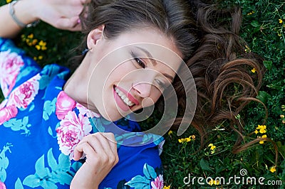 Beautiful happy woman lying on the grass with yellow flowers Stock Photo