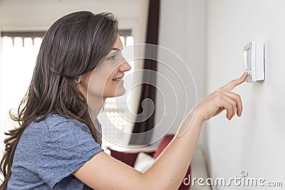 Beautiful happy woman push button digital thermostat at house Stock Photo