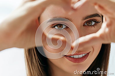 Beautiful Happy Woman Showing Love Sign Near Eyes. Stock Photo