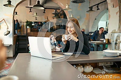 Beautiful happy woman working on laptop computer during coffee break in cafe bar Stock Photo