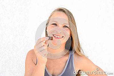 A beautiful happy 35 years blonde woman with a chocolate candy in her hands. Close up portrait Stock Photo