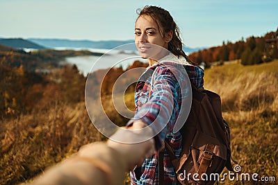 Beautiful hiker woman standing on slope of mountain ridge and holding hand, to follow her Stock Photo
