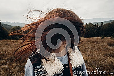 beautiful hipster traveler having fun in windy mountains, playing with hair. stylish woman hiking. wanderlust and travel concept Stock Photo