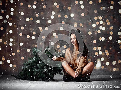 Beautiful hipster woman with Christmas fir tree and lights in knitted sweater blouse Stock Photo
