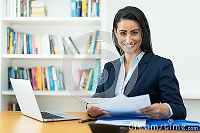 Beautiful hispanic mature businesswoman working with documents at desk Stock Photo