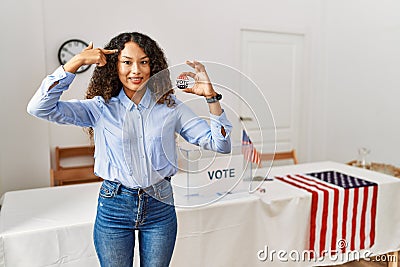 Beautiful hispanic woman standing by at political campaign by voting ballot smiling pointing to head with one finger, great idea Stock Photo
