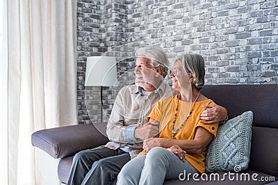 Beautiful hoary good-looking mature spouses relaxing together on comfy couch at modern home smiling staring at camera feel Stock Photo