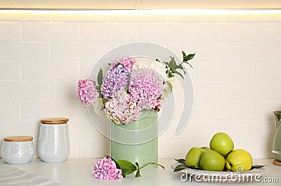 Beautiful hydrangea flowers and apples on countertop Stock Photo