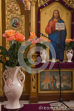 Beautiful icons with roses in flower pots. Religious images in christian cathedral. Religious art. Christian church interior. Editorial Stock Photo