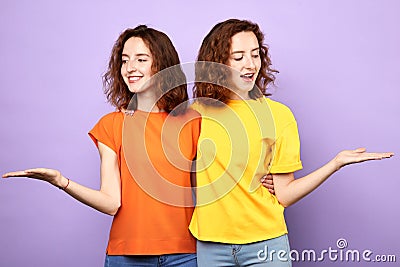 Beautiful identical sisters twins holding copyspace on the palms Stock Photo