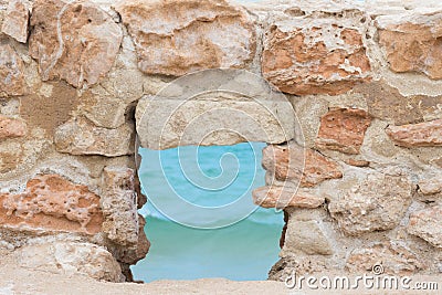 View of Turquoise Sea Ocean through Window in Ancient Fortress Stone Wall. Travel Vacation Tranquility Contemplation Freedom Stock Photo