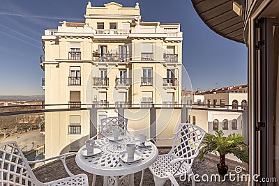 Beautiful image of a terrace with a circular white outdoor table with matching chairs and a view of a beautiful vintage building Stock Photo