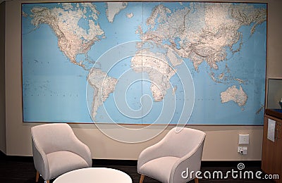 Beautiful interior with two modern armchairs a small white table and massive world map in background Stock Photo