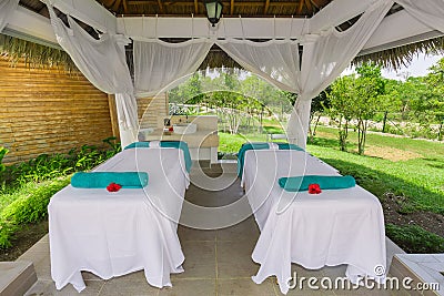 Beautiful inviting view of cozy comfortable massage beds standing inside gazebo in tropical garden Editorial Stock Photo