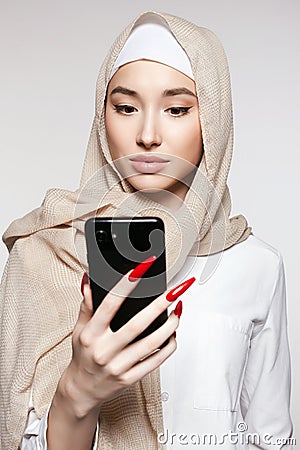 beautiful islamic young woman with smartphone. beauty girl in hijab looking at the screen Stock Photo