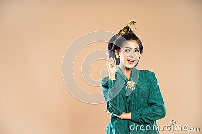 beautiful javanese woman in green kebaya standing looking up with pointed finger Stock Photo