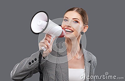 A beautiful joyful girl shouts into the loudspeaker on isolated pink background Stock Photo