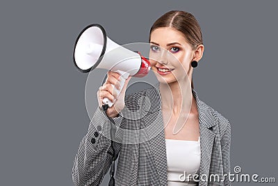 A beautiful joyful girl shouts into the loudspeaker on isolated pink background Stock Photo