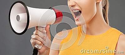 A beautiful joyful girl shouts into the loudspeaker on isolatedgrey background Stock Photo