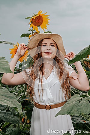 Beautiful joyful woman in blooming sunflower field. Smiling girl with sunflower on field, outdoors. Girl in light beige Stock Photo