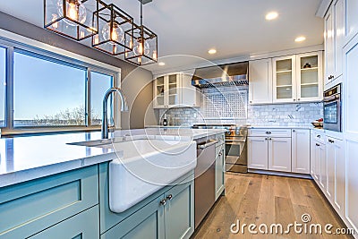 Beautiful kitchen room with green island and farm sink. Stock Photo